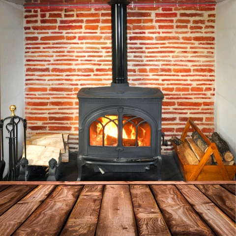 Intérieur avec poêle à bois en fonte noire allumé, flammes visibles à travers les vitres cintrées