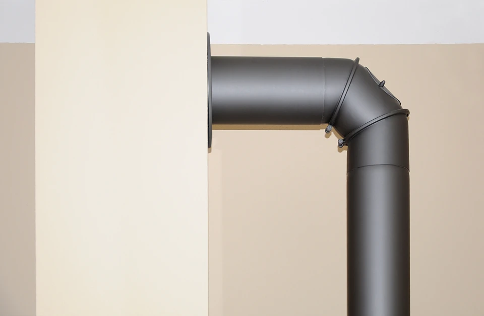 Salon moderne et épuré avec un poêle à bois cylindrique design, modèle à accumulation en pierre naturelle grise et acier émaillé noir